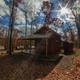 Exterior shot of a single cabin on wooded grounds with surrounding trails and site features; good for illustrating the cabin setting and landscape on the property.