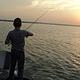 A young man fishing at sunset
