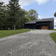 Exterior image of 'The Lakehouse' on NEOC property with gravel drive and lake in background (page context: The Lakehouse — New England Outdoor Center). Good to show a distinct on-site building and waterfront access.