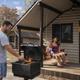 Cabin exterior with porch, picnic table and on-site grill being used — good representation of the campground's cabin lodging and outdoor amenities.