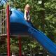 Playground slide with trees and parked cars in background — represents family play area on the property; originates from the amenities/gallery section.