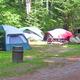 Clear campsite group view showing multiple tents, picnic table and an RV in a wooded campground area — good overall campground scene from the property’s camping page.