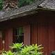 Cabin with red siding in front of conifer forest
