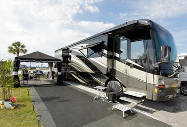 On-site RV pitch with a large motorhome, awning, outdoor mat and patio setup — demonstrates typical RV site size and setup at the resort (used on the property gallery).