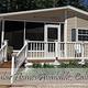 Clear photo of a manufactured home/cabin on site with gravel pad, deck and surrounding pines — useful to show seasonal/long-term lodging (found on the property homepage gallery).