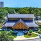 Clear photo of the main clubhouse / facility building on the property with surrounding grounds and distant beach visible — useful facility image.