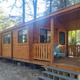 Exterior of a rental cabin with porch and campground surroundings — useful for showcasing cabin lodging. Located in the site’s campsites/cabins gallery (Cabin-1) on the property website.