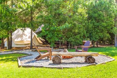 Another campsite composition with tent, firepit and seating that highlights the wooded setting and site layout; from the glamping page (100_tg2_5625).