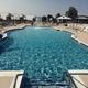 Large outdoor swimming pool with deck chairs and fencing — good depiction of the resort’s main pool facility as presented on the site.