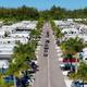 High-angle view looking straight down a main park street lined with RVs and palm trees; highlights site spacing and community events (file labeled bayfest-parade on the property site).