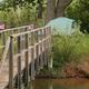 Footbridge over water with picnic table and a tent visible — shows campsite access, tent camping and campsite setting.