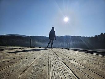 A  person stands silhouetted at the end of the dock at South Skookum Lake Campground. 