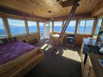 Interior of a lookout, with ladder, bed and stove
