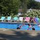 Ground-level pool photo showing swimmers, lounge chairs and poolside setting — good detailed shot of on-site pool facilities (used as a background/section image on the site).