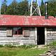 A rustic wood cabin with a red roof surrounded by trees and grass