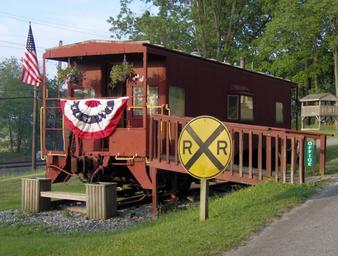 Clear photo of the distinctive red caboose building used as on‑site feature/office, with ramp and railroad crossing sign — good property-identifying image from the homepage.