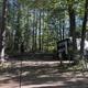 Campsite view showing an RV on a cleared site with pedestal hookups and wooded surroundings — good depiction of actual RV/campsite layout from the Layout page.