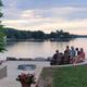 Waterfront communal fire-ring seating overlooking the lake with guests — highlights shared amenities and the scenic shoreline setting (source page: /amenities/).