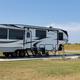 Deluxe pull-through RV site on concrete pad with grassy foreground and open horizon — shows site type and spacing typical at the park (from the rates/amenities pages).
