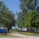 Another panorama of RVs and tow vehicles at sites with picnic tables and trees — good alternate view of typical RV pitches and site spacing on the property (homepage slide).