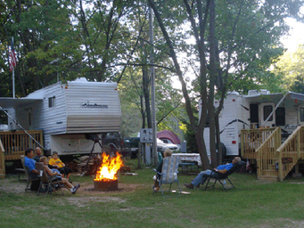 Campfire area between park-models/RVs with guests seated — shows typical campsite atmosphere and firepit facilities (Pictures page image).