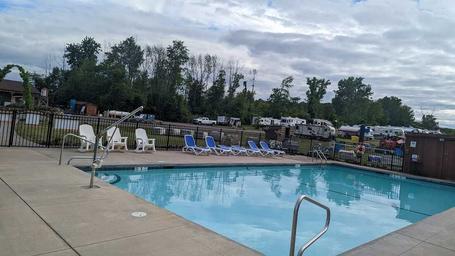 Photo showing the swimming pool with lounge chairs and RVs visible beyond the fence — useful to highlight on-site amenities (from About/Resort pages).