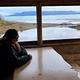 A lodger views Lake Clark through a window inside Priest Rock cabin