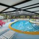 Covered outdoor pool area with loungers and RV visible in background — highlights on-site recreation facility.
