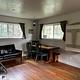 Front room of cabin showing  table, chairs, couch and two windows. 
