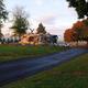 Wide view of park grounds with paved drive, grassy areas, trees and stone landscaping — useful overall site view. Originates from the park homepage banner showing on-site scenery.