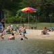 Beach area on the lake with people, umbrella and swimming shore — demonstrates waterfront/beach amenities (from the Camping photo gallery).