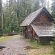 Fire ring in front of log cabin with attached, covered wood shed  in the forest.