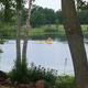 Lakeside shot showing people paddling on Snow Lake framed by shoreline trees — good scenic view of on-site water recreation; image appears on the 'Our Campground' page.