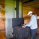 A woman cooking on stove in Gut Island cabin 1