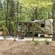 RV/pull-through site with paved pad, fire ring and seating in a wooded setting — clearly shows the RV accommodations and site layout (from the campground's 'ways to stay' photo group).