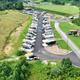 Wide aerial photograph showing the campground layout with rows of RVs, paved roads, and on-site buildings; good overall property overview matching the listed RV park.