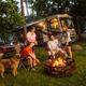 Hero photo on the Port Huron KOA campground page showing an RV site with patio area, trees, and a family around a fire ring — clear on‑grounds campsite view from the campground’s own hero image URL.