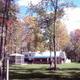 Open grassy area with trailers, building and mature trees showing campground common area and facilities; from the Whitetail Ridge Campground Photos gallery on the site.