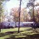 Clear campsite/RV row with grassy area, fire ring and trees; image is from the campground’s main photo gallery page (Whitetail Ridge Campground Photos) showing on-site RV pitches and grounds.