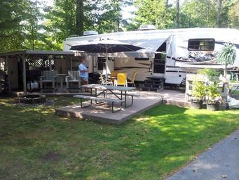 RV site with full hookup fifth‑wheel, patio area, picnic table and fire pit — depicts the campsite setup and guest accommodations (used on the campground’s main page content).