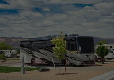 Photograph of a large motorhome on a spacious, landscaped site with picnic table and concrete patio — highlights the resort’s large/luxury RV sites (image used in ‘Large, Luxurious Sites’ site section).