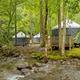 Group of yurts beside a stream in a forested area — strong, scenic photo that corresponds to the site’s yurt accommodations and the campground’s creekside setting.
