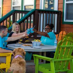 Guests seated at a table in front of cabin-style lodging; shows cabin exterior, patio seating and campground hospitality/amenity setting. (waystostay photos).