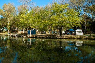 Pond with reflected trees and tents along the shoreline — scenic on-site water feature visible on the property page (page: https://www.woodsvalley.com/our-campgound/).