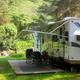 Large RV parked on a prepared site with a deck and picnic area adjacent to the river — useful example of RV accommodations and river access (slide01 on the site).