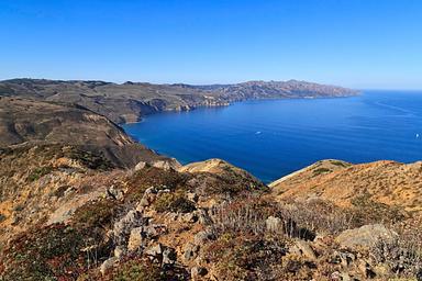 View from a high ridge overlooking the rest of a long, narrow, rugged island with steep cliffs  