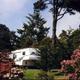 Close view of an RV parked among landscaping and flowering shrubs, illustrating individual site setting and vegetation (About page).