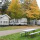 Clear view of an RV campsite row with park models/trailers, picnic table and gravel drive — good overall site layout photo (from property gallery page).