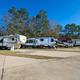 Wide-angle shot of multiple pull-thru/back-in RV sites and paved roads showing layout, landscaping and large rigs — strong overview of the park’s RV accommodations (from rates/gallery pages).