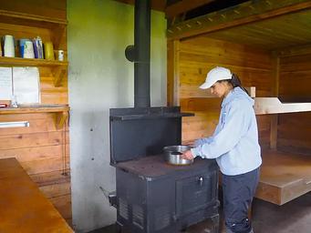 A woman cooking on stove in Gut Island cabin 1